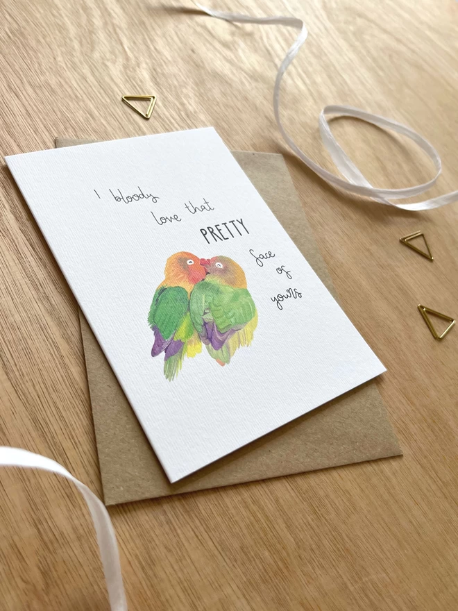 a greetings card featuring two love birds kissing each other with the phrase “I bloody love that pretty face of yours”