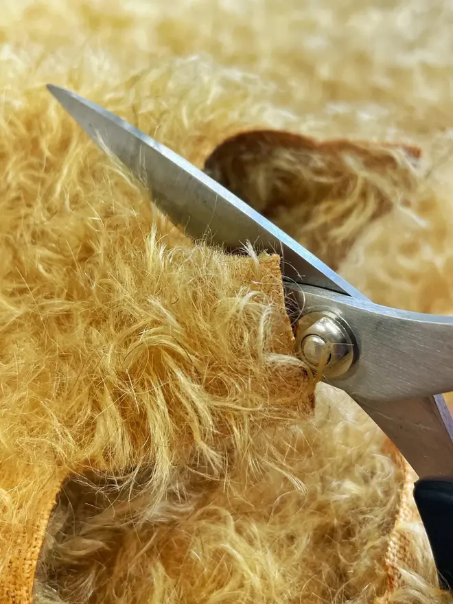 Close-up of teddy bear fabric being cut. 