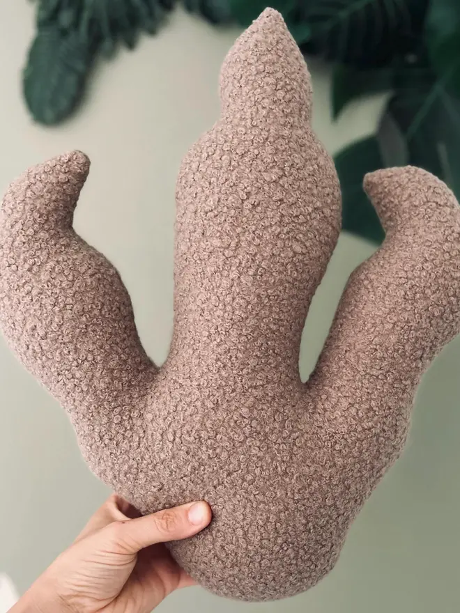 boucle dinosaur footprint cushion. a beige dinosaur foot cushion.
