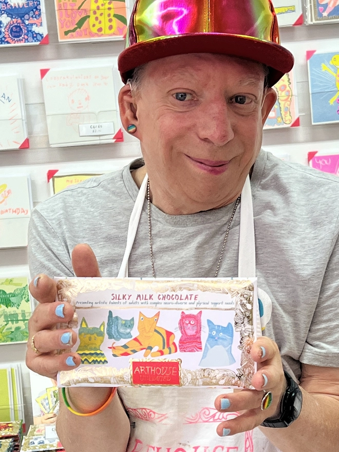 Artist holding silky smooth charity milk chocolate bar with hand drawn colourful cats on wrapper 