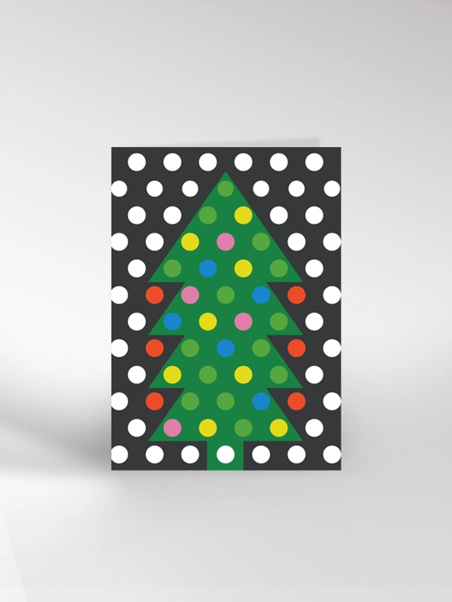 Contemporary illustrated Christmas card of a tree covered in lights with falling snow