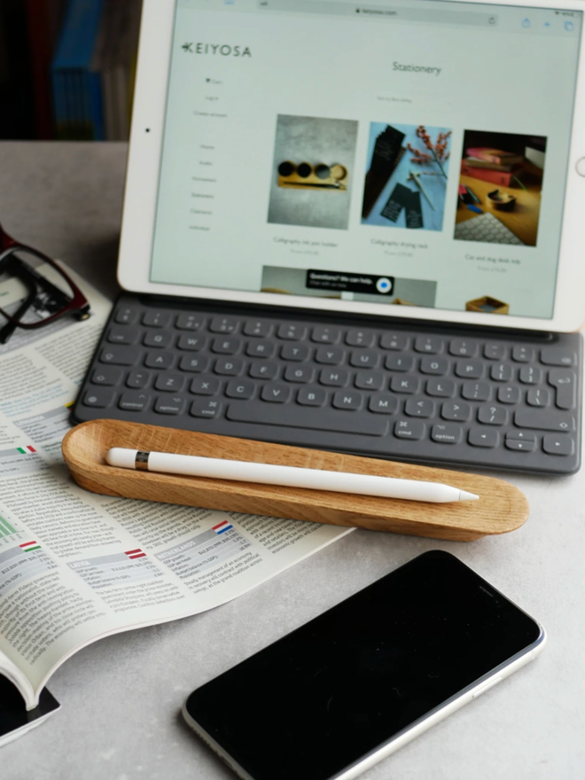 Pen Rest. The pen rest, containing an iPad stylus, is set out in front of a laptop.