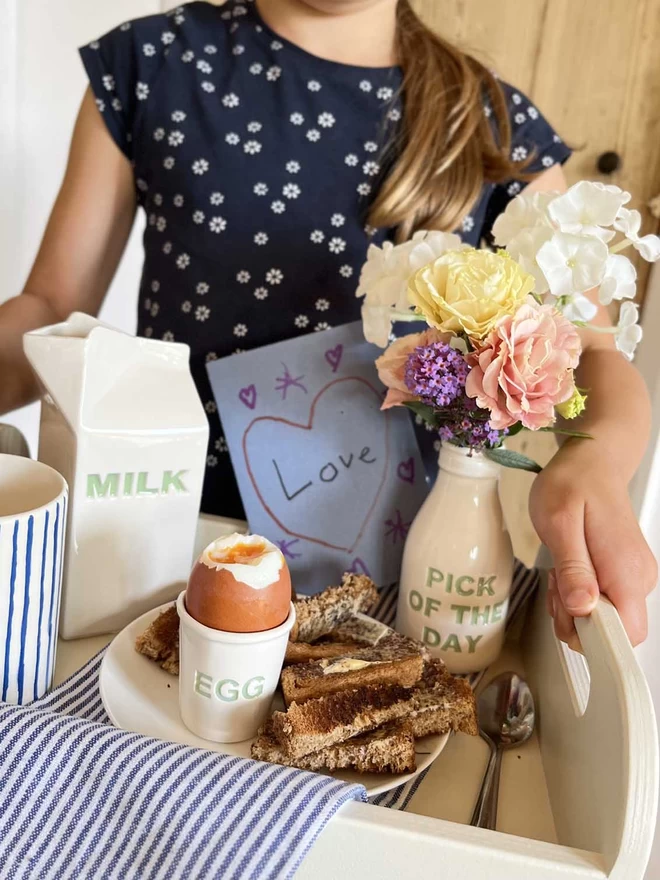 A Child has prepared a breakfast tray, finished off with a ‘pick of the day’ bottle filled with flowers.