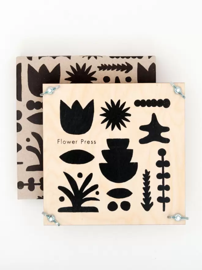 Flower press with a bold black abstract printed front, sat on top of it's card display box with matching abstract pattern.