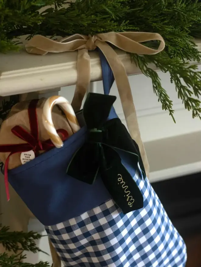 blue gingham stocking with dark green velvet bow, embroidered with a name