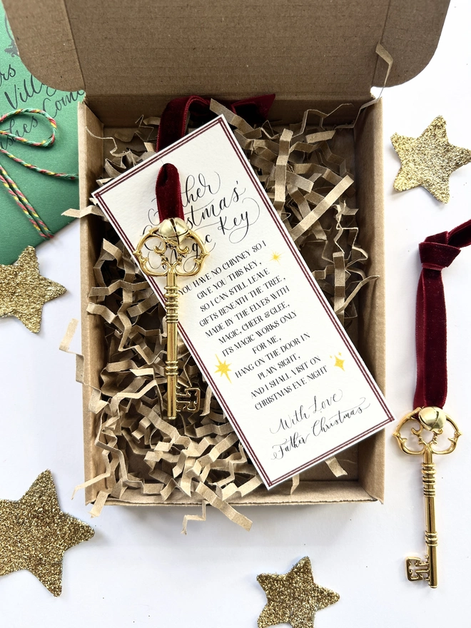 Golden Father Christmas Key attached to poem card and adorned with red velvet ribbon and small golden bell in box with eco friendly packaging