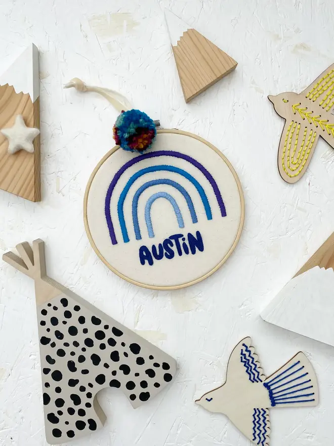 personalised name and rainbow embroidered hoop. cotton hoop embroidered with the name arthur and a rainbow in different shades of blue.