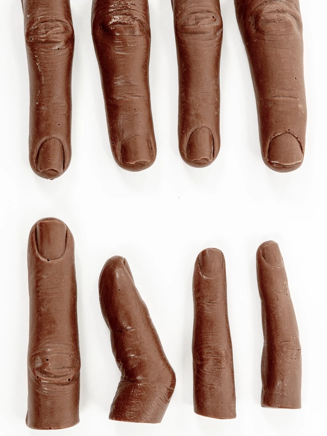 Realistic milk chocolate human fingers on white background