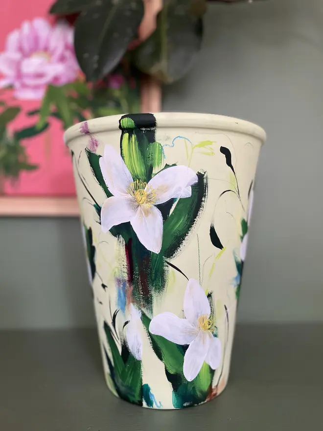 Hand painted floral terracotta plant pot pale green background with clematis flowers