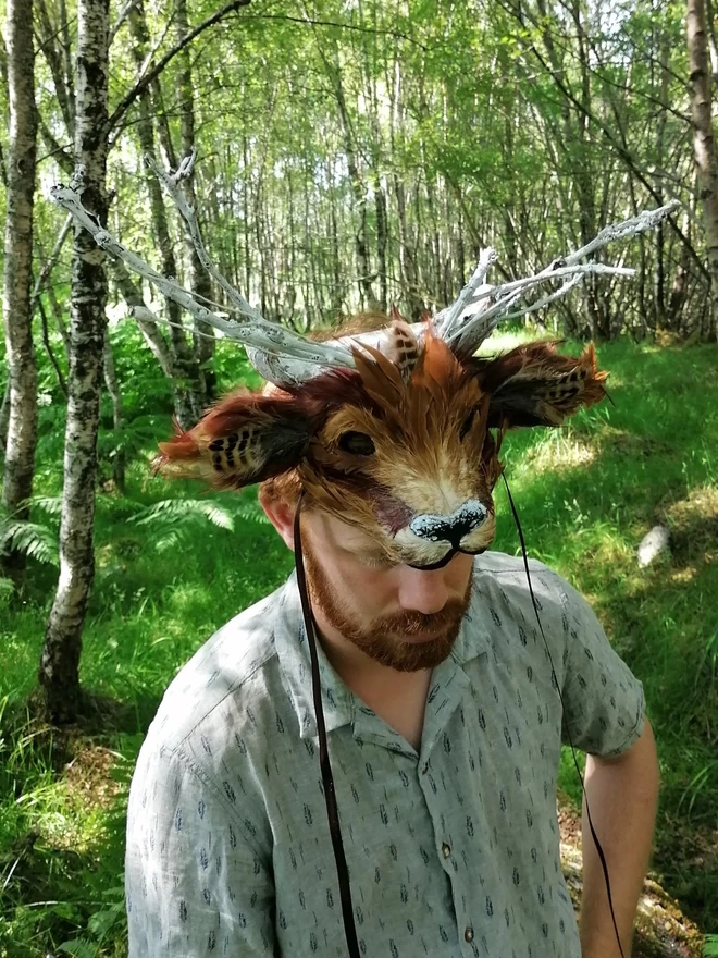 A man wearing a luxury brown deer part mask atop his head as a headdress