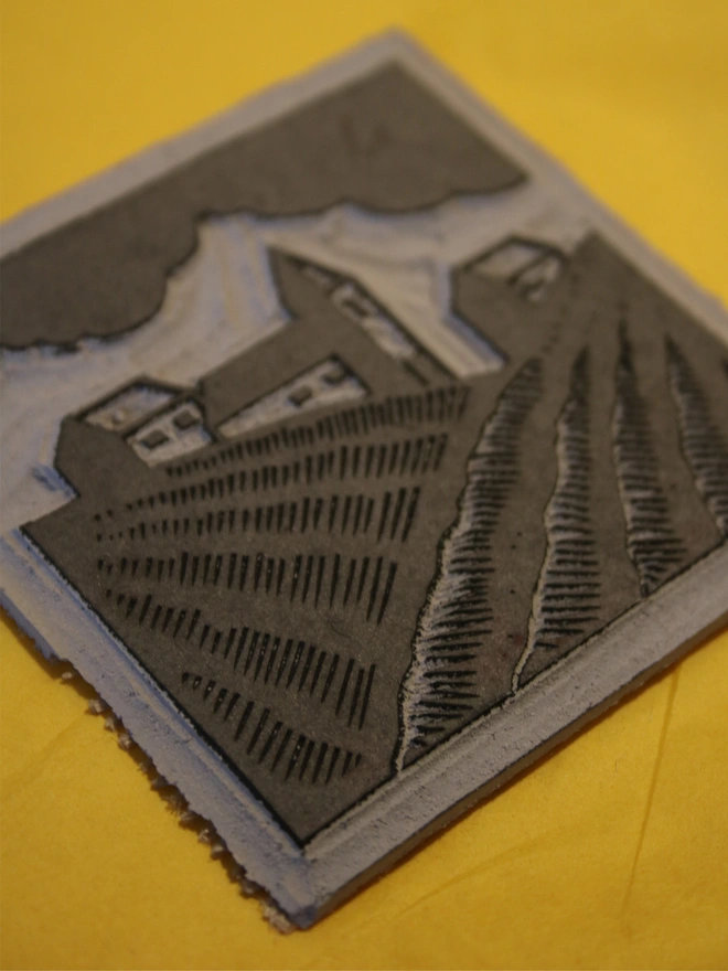 Linocut block carved to show rural farmland and houses