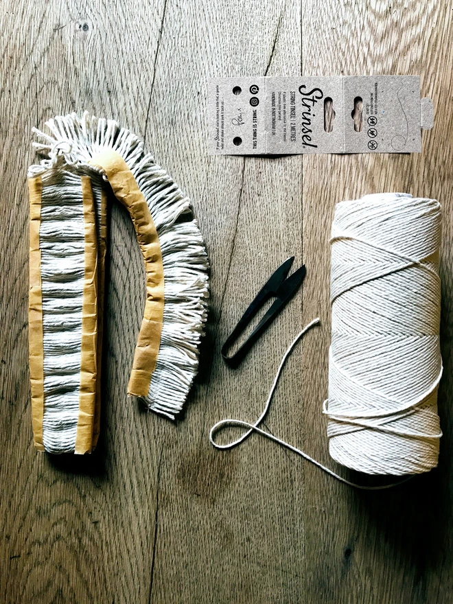 Cotton string tinsel - Strinsel - part made on an oak table with hand tools, string spool and kraft label