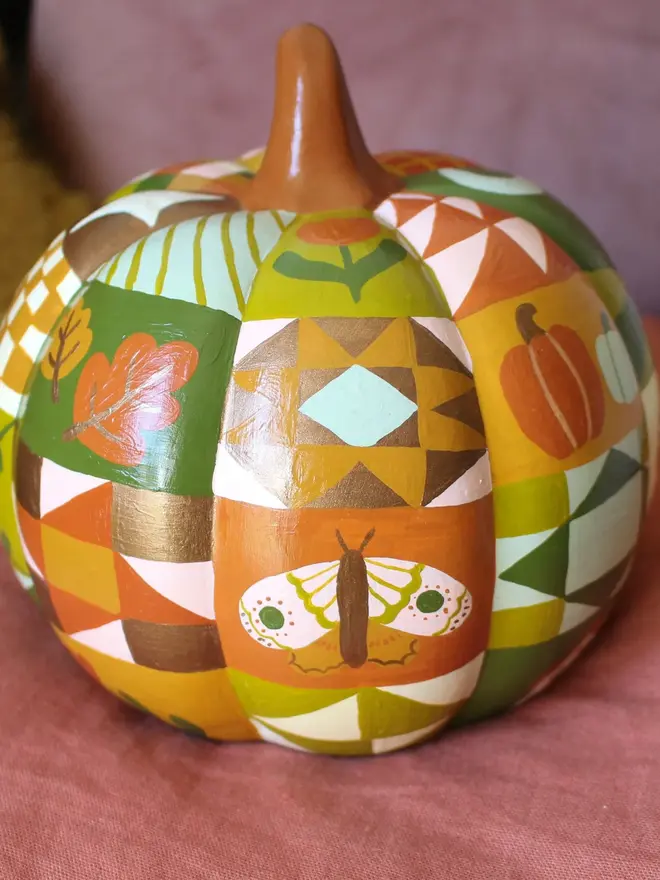 hand-painted woodland ceramic pumpkin. a ceramic pumpkin painted with patchwork colours and patters, alongside mushrooms, moons, stars and flowers.