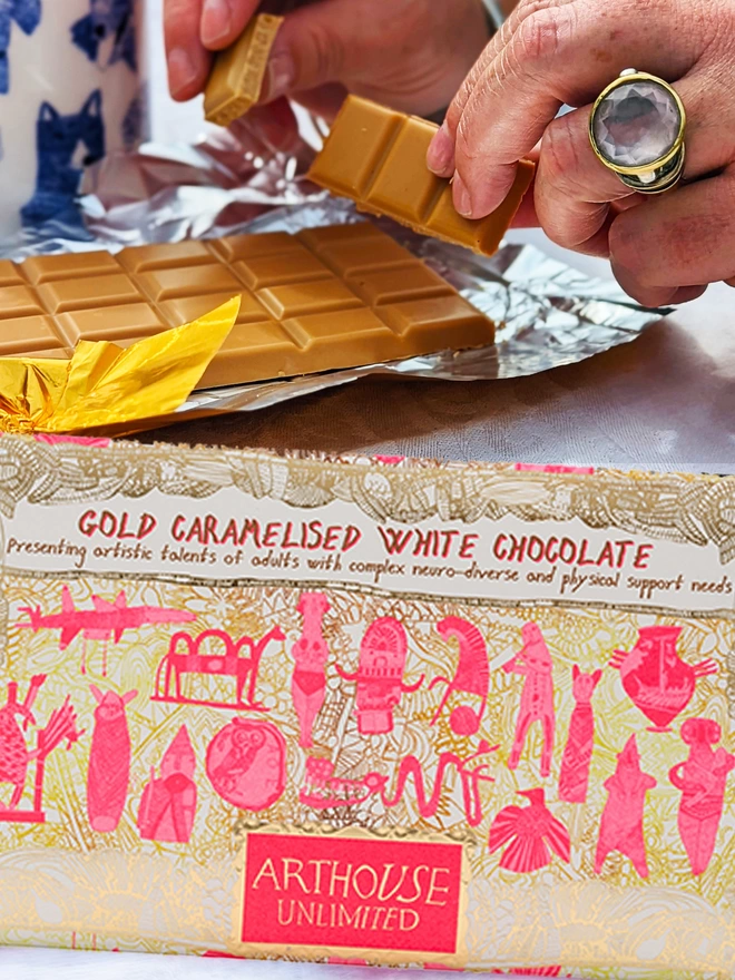 Charity gold caramelised white chocolate bar wrapped in foiled card with pink ancient drawings 