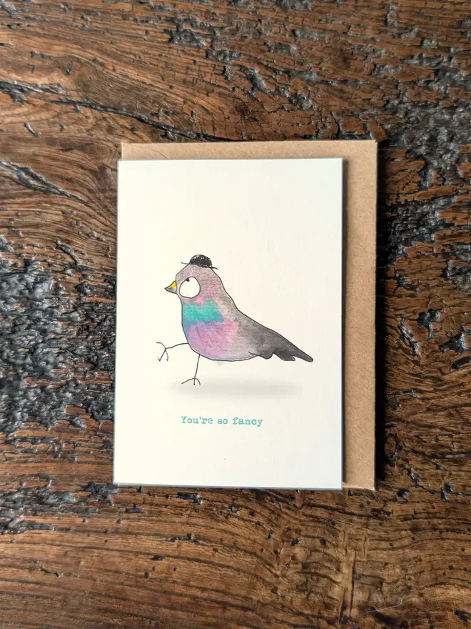 Flat lay of a greeting card with a pigeon wearing a hat