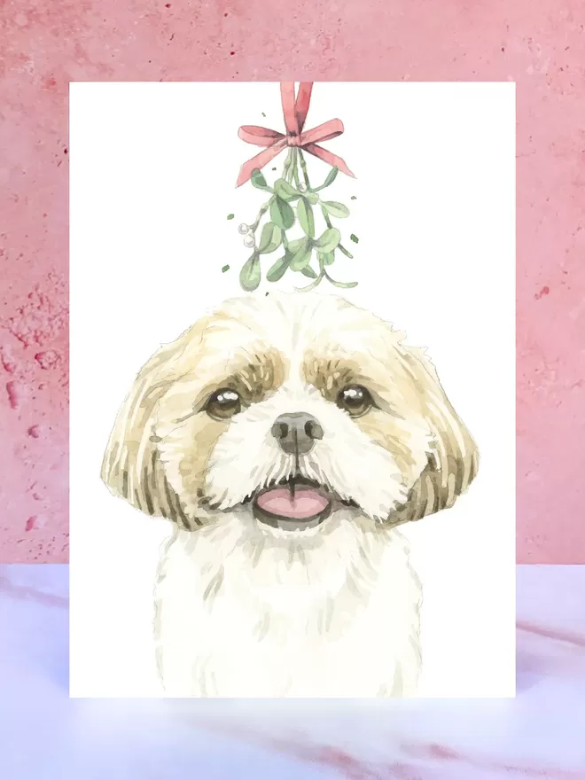 A Christmas card featuring a hand painted design of a Shih Tzu, stood upright on a marble surface.