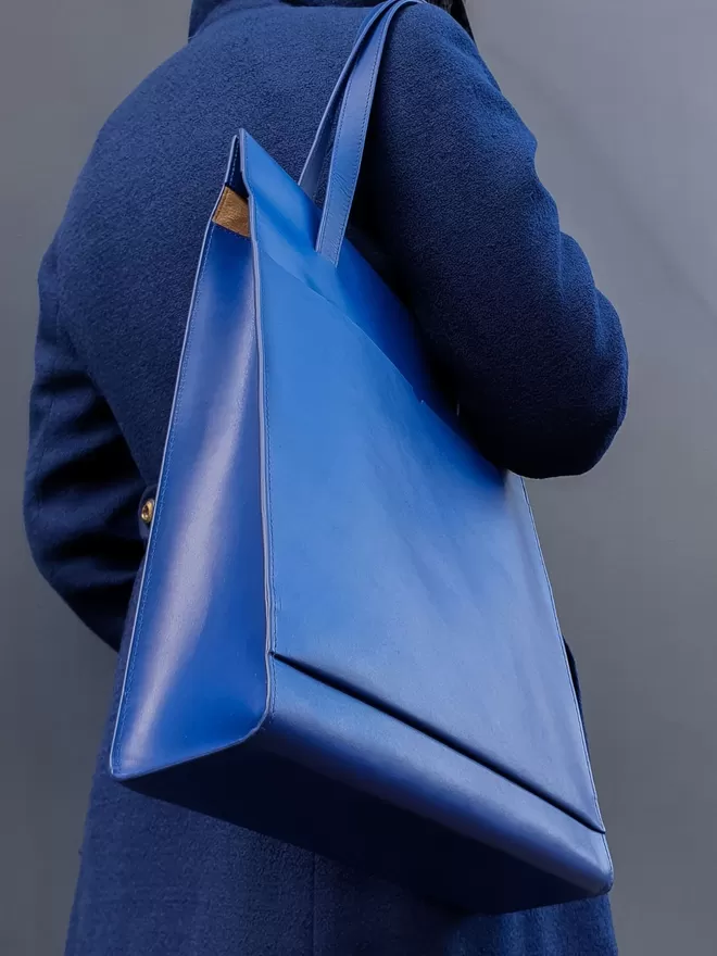 Bottom up image of the cobalt blue tote bag worn on a royal blue long length coat.