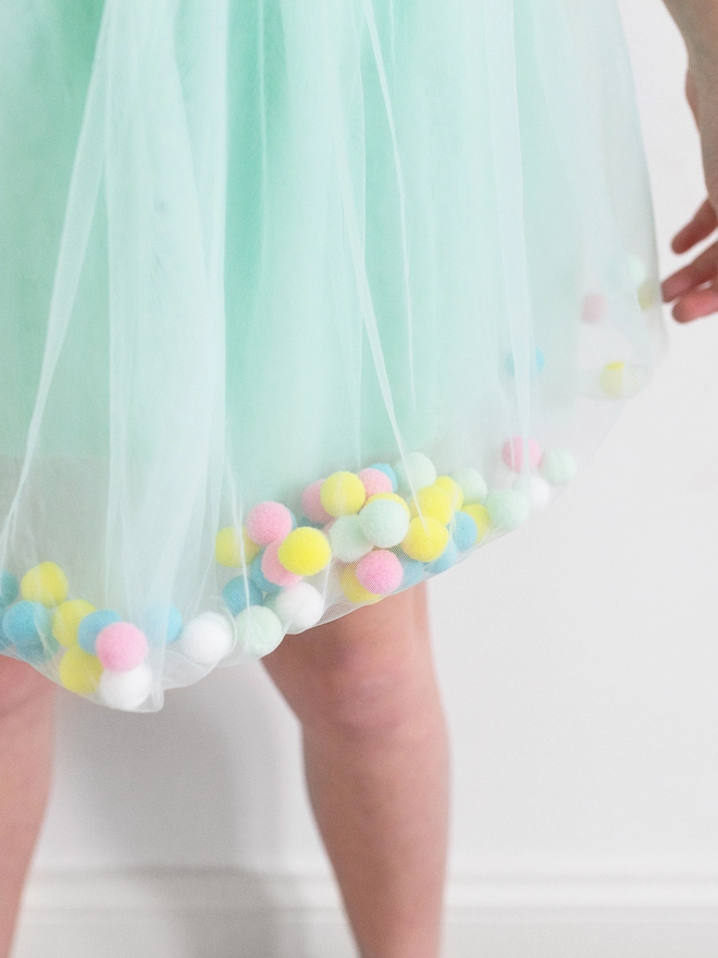 A picture of a mint green tulle pom pom tutu with multi coloured pom poms