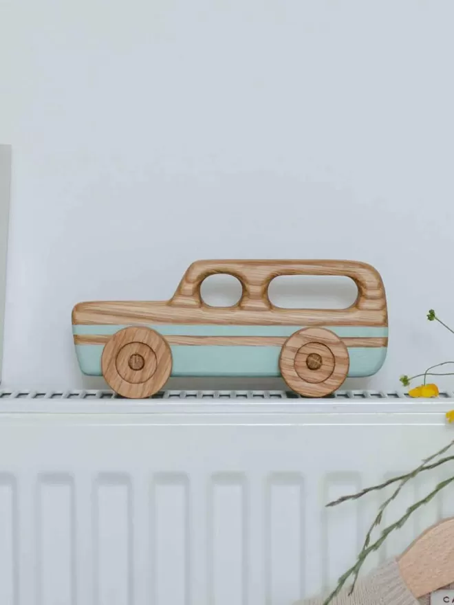 Wooden Toy Car Station Wagon resting on a radiator with a side view of the toy