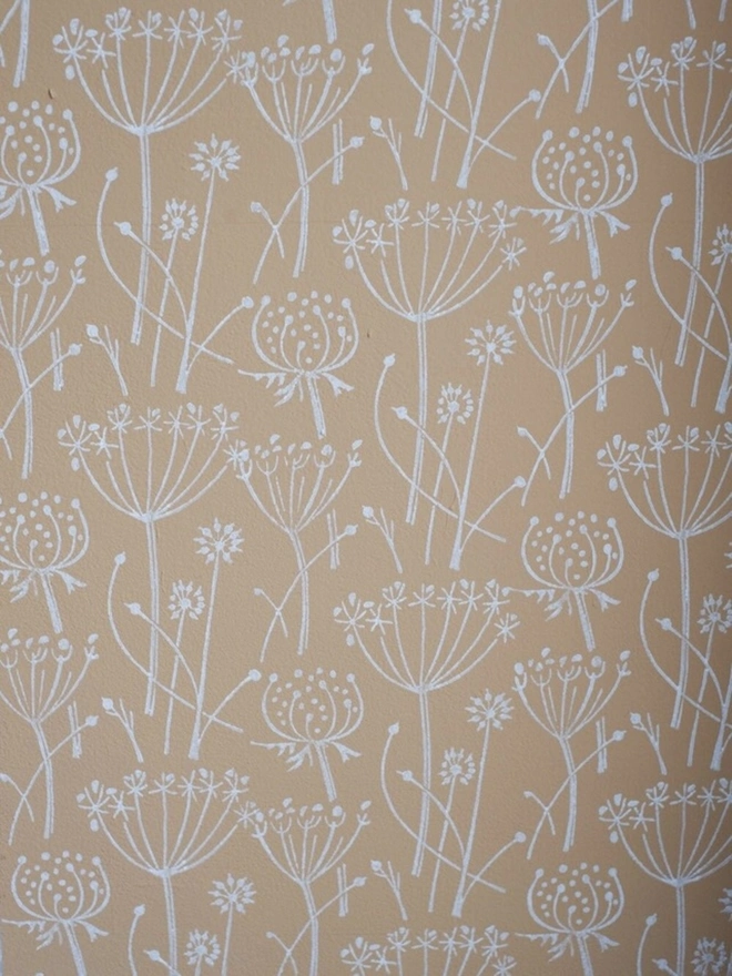 Tussock Patterned Paint Roller, a yellow and white floral pattern on the wall behind. 