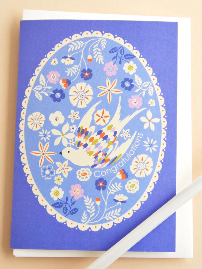 purple card with oval design with flowers and birds and 'congratulations' text