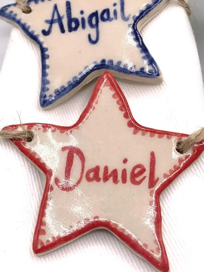 Personalised Ceramic Christmas Star Name Place Markers, a colourful star place marker sitting on a plain white surface. 