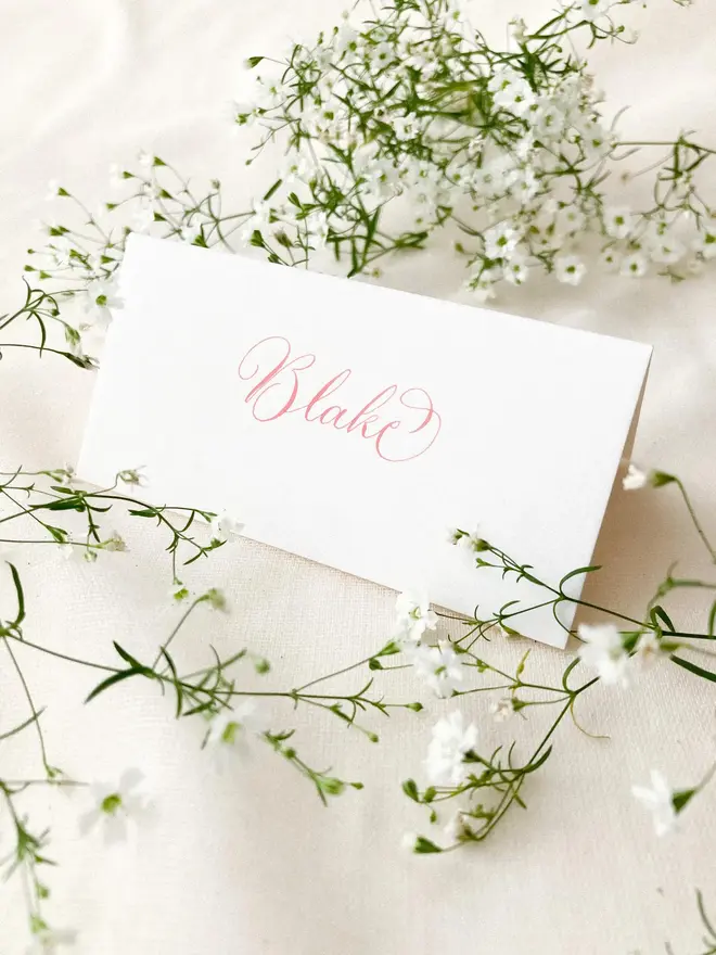 personalised calligraphy place cards. white place card with name in calligraphy pink ink.
