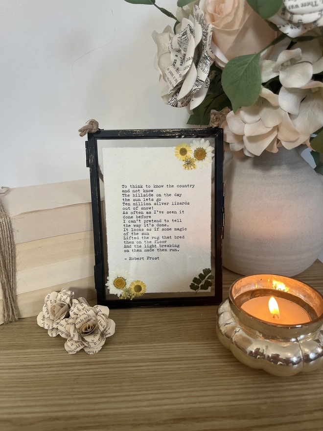 Framed typewriter print hand typed with an antique typewriter onto cotton rag handmade deckled paper. It is displayed in a black hanging rustic frame with gold brush detailing and decorated with real pressed dried flowers.