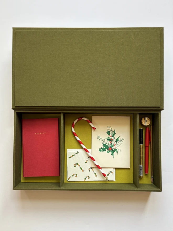 Open handmade Christmas Correspondence box in Olive green cloth displaying cards and stationery items including Keep Collect Christmas Naughty or Nice notebook