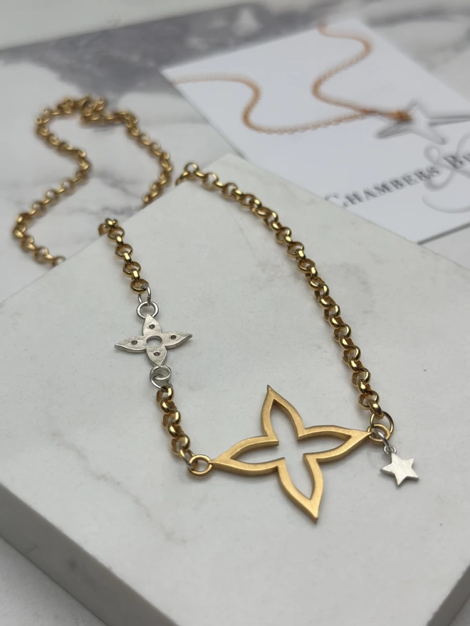 gold chain with large gold plate flower charm, small sterling silver flower inset in chain and mini silver star charm