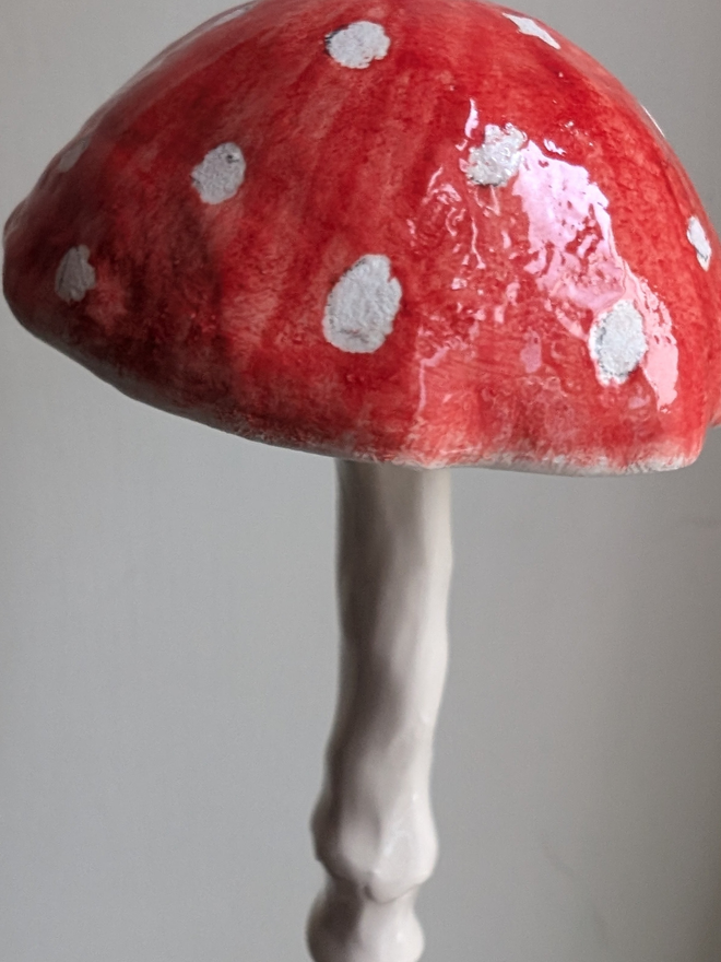 red and white spotty pottery mushroom hanging bell decoration against a pale grey background