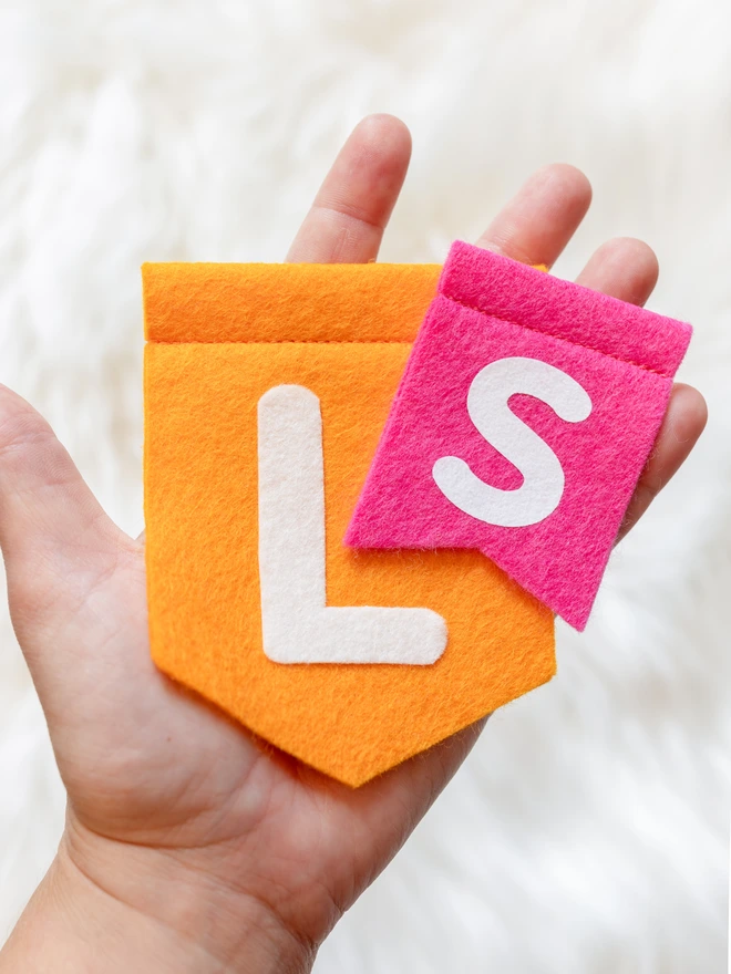 a hand holding 2 felt flags, showing the size difference between small and large.
