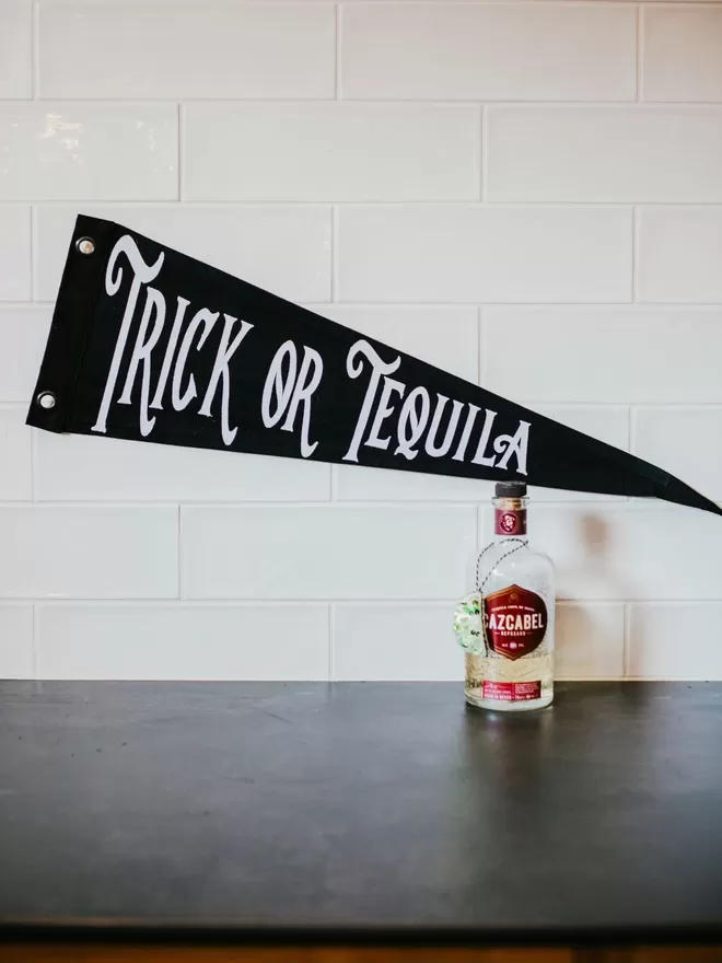 Trick or Tequila Pennant flag by Caro B. seen with a bottle of tequila.