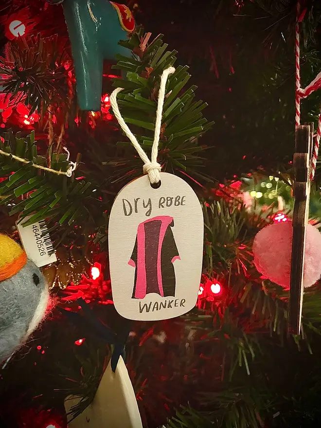 Dry Robe Wanker ornament hangs on christmas tree amongst other joyous ornaments