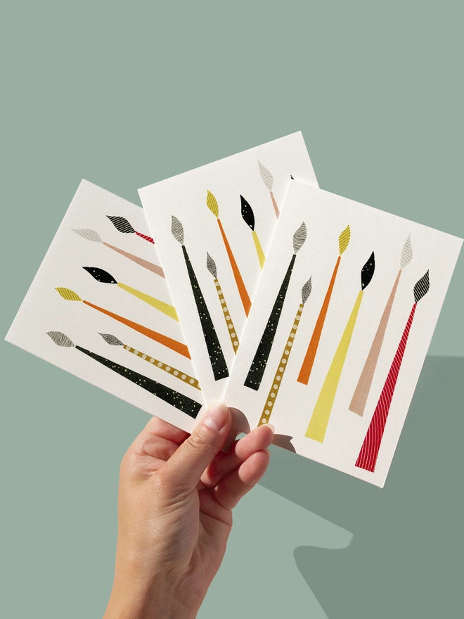 A Christmas card featuring mid century style festive candles in rich colours.