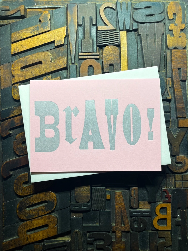 A congratulatory letterpress candy pink card featuring the deep impression word "BRAVO!"; in bold metallic gold letters with a set of colourful envelopes. Perfect for exam results and graduations and other celebrations and milestones.