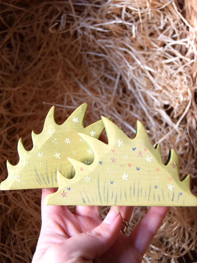 flower patch wooden toy being held in hand above woodwool