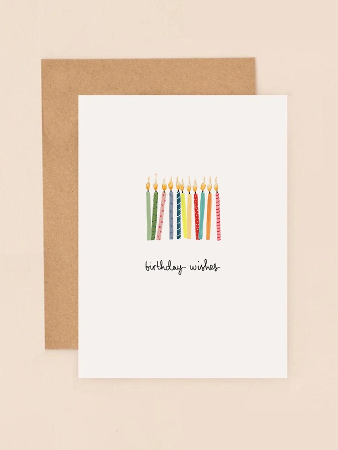 A vibrant illustration featuring a collection of colorful birthday candles in shades of red, yellow, blue, and green, each with a flickering flame. The candles are arranged in a playful, haphazard style, conveying a festive atmosphere. Above the candles, the handwritten message "Birthday Wishes" adds a personal and cheerful touch. The design is minimalist and charming, perfect for celebrating a special occasion.