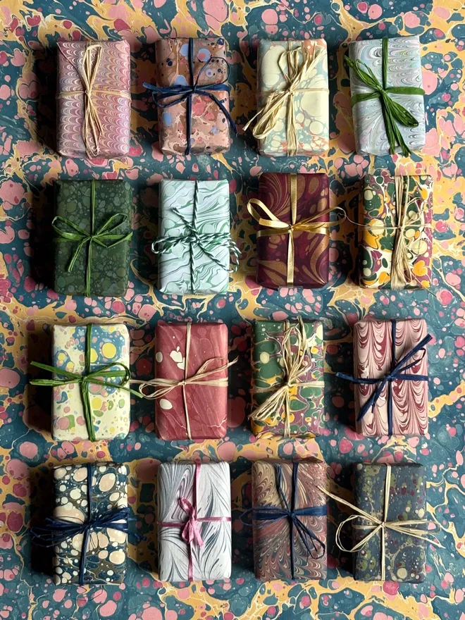 Set of 3 Wrapped Soaps. A selection of three soaps wrapped in multicoloured paper, tied with twine.