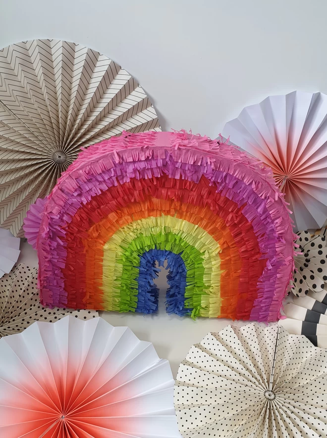 rainbow pinata on a background of paper decorations
