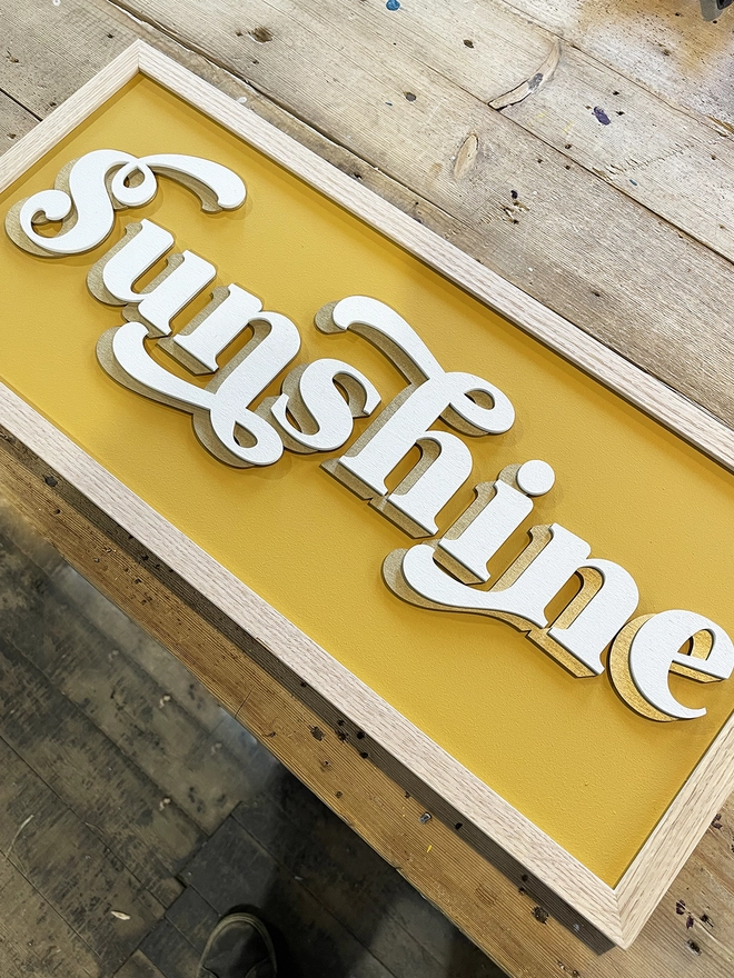 a close up of a wooden painted sign which reads SUNSHINE 