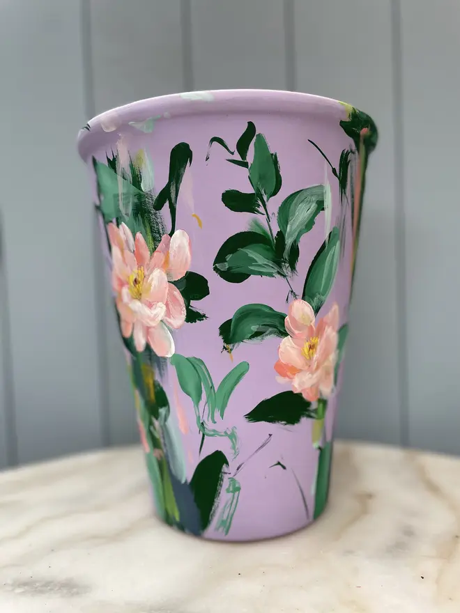 Unique hand-painted terracotta pot featuring apricot geum flowers on a lilic background