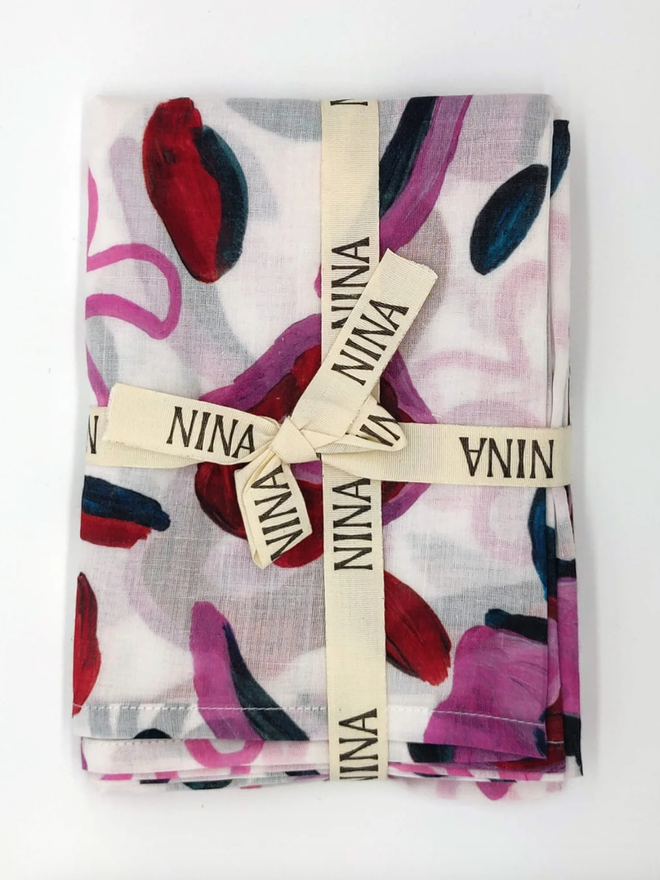 Abstract Flowers Muslin. A muslin with a purple abstract flower design, folded.