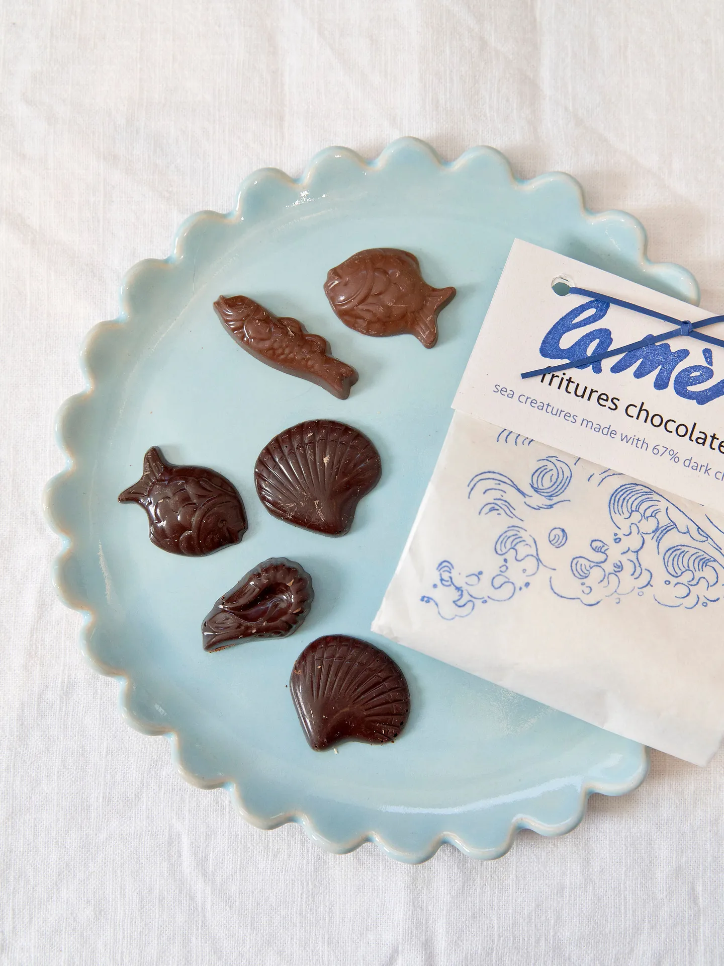 milk and dark chocolate sea creatures on blue plate, next to white paper pouch