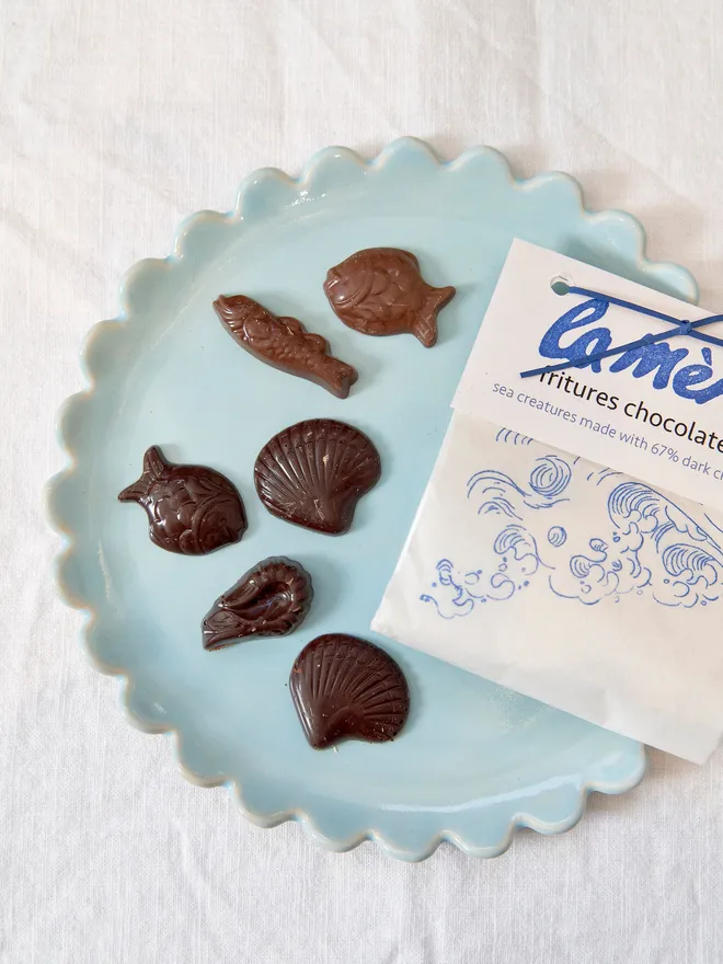 milk and dark chocolate sea creatures on blue plate, next to white paper pouch