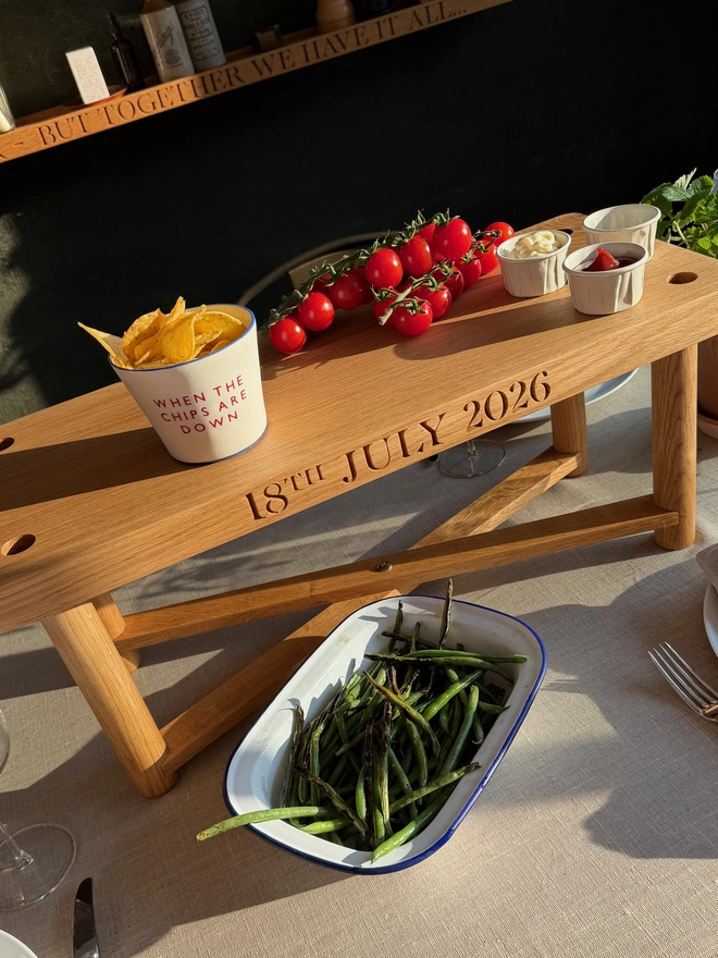 Oak swing seat on its legs used as a raised serving stand, engraved with a wedding date