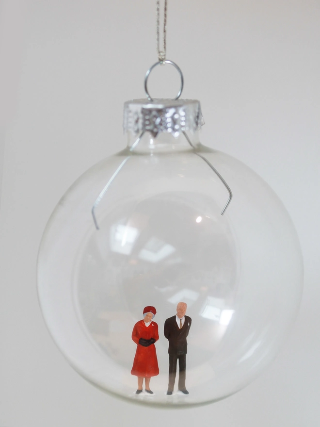 Miniature figure of Queen Elizabeth and Price Phillip in a glass Christmas bauble