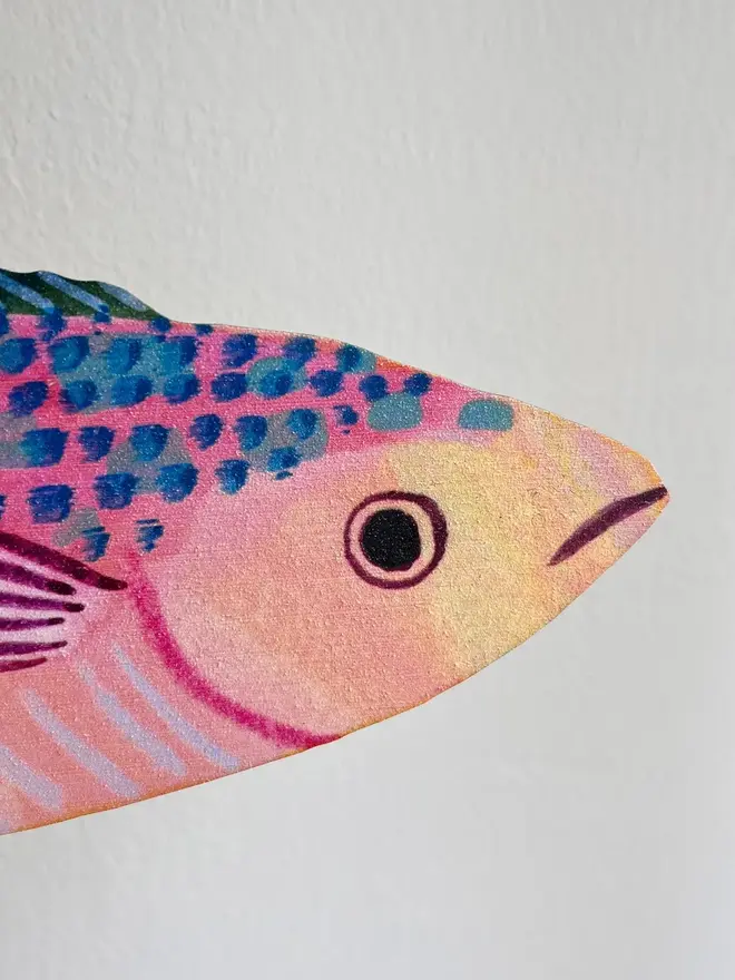 wooden mackerel wall decoration. mackerel decoration hung up on white wall, zoomed in on head.