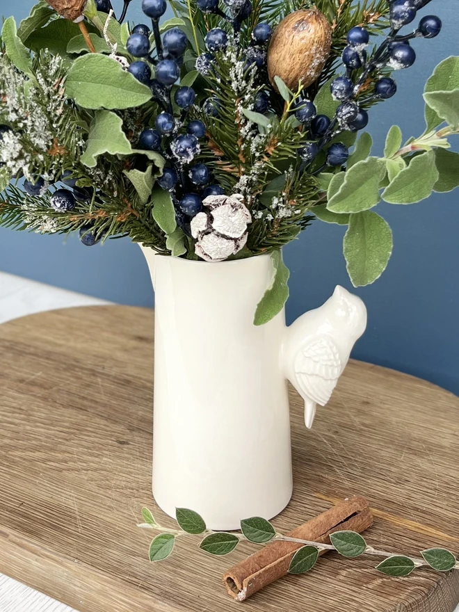 Ceramic jug with a detailed bird handle fill with Christmas foliage