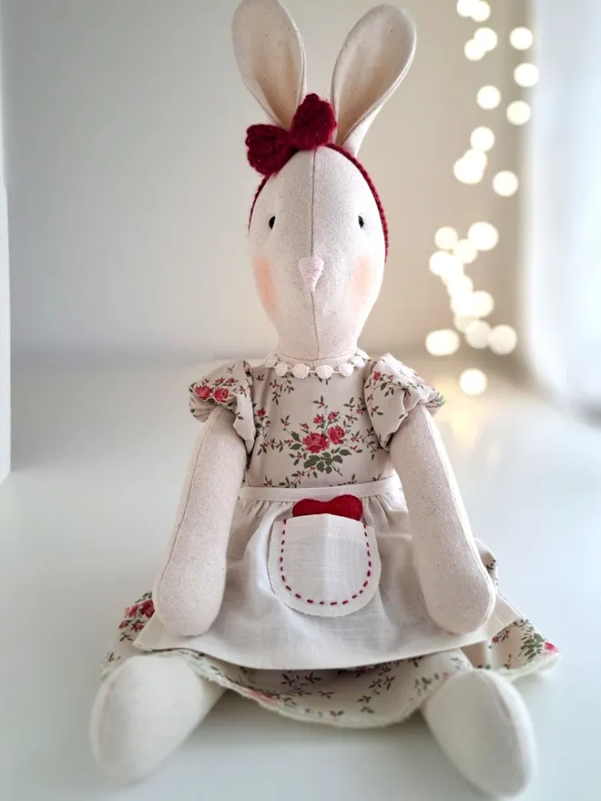Front view of Veronica Bunny handmade as an heirloom soft toy, featuring hand-embroidered details and a floral dress with linen apron